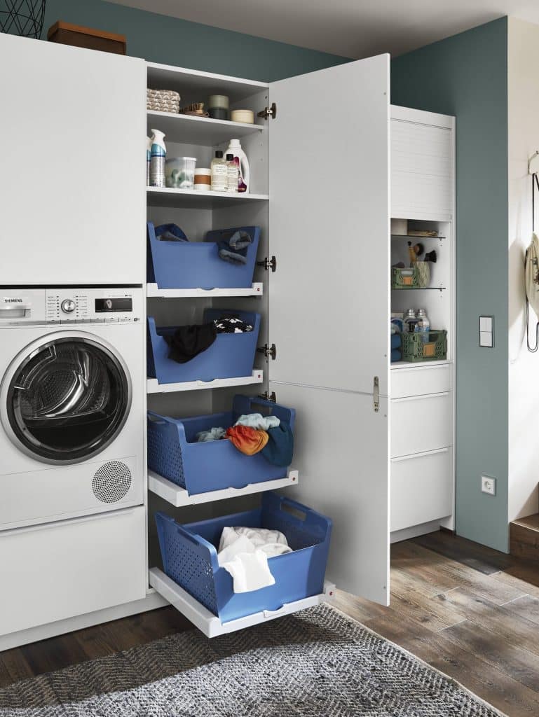 Une machine à laver en hauteur à gauche de grands tiroirs avec des bacs de rangements