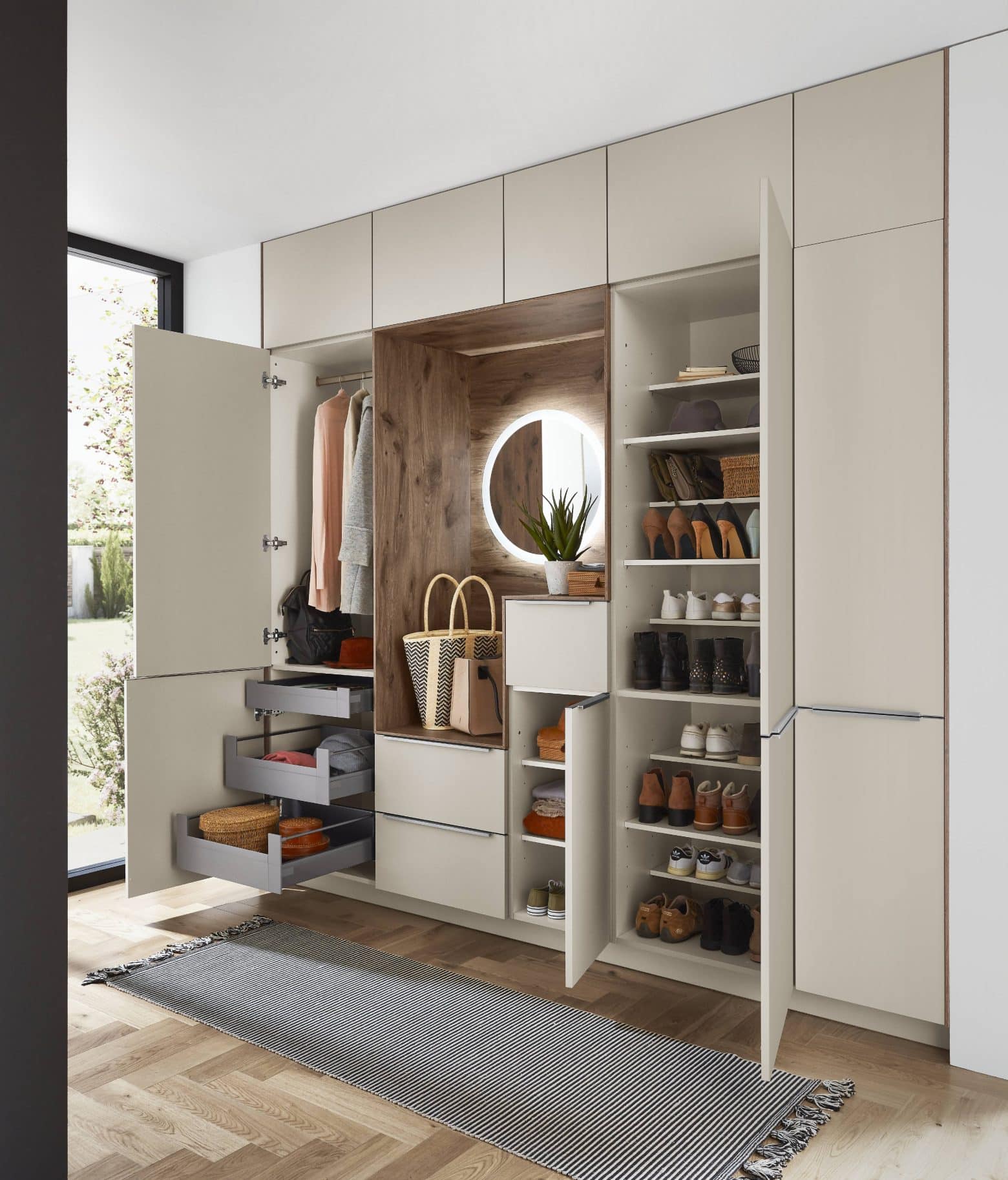 Dressing ouvert avec vêtements rangés et un miroir rond lumineux