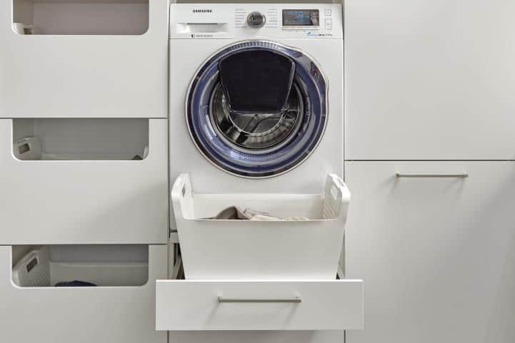 Une machine à laver au-dessus de tiroirs de rangements blanc