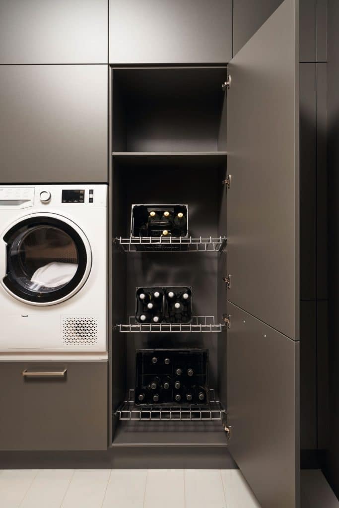 Une machine à laver en hauteur à gauche d'un placard à rangement ouvert