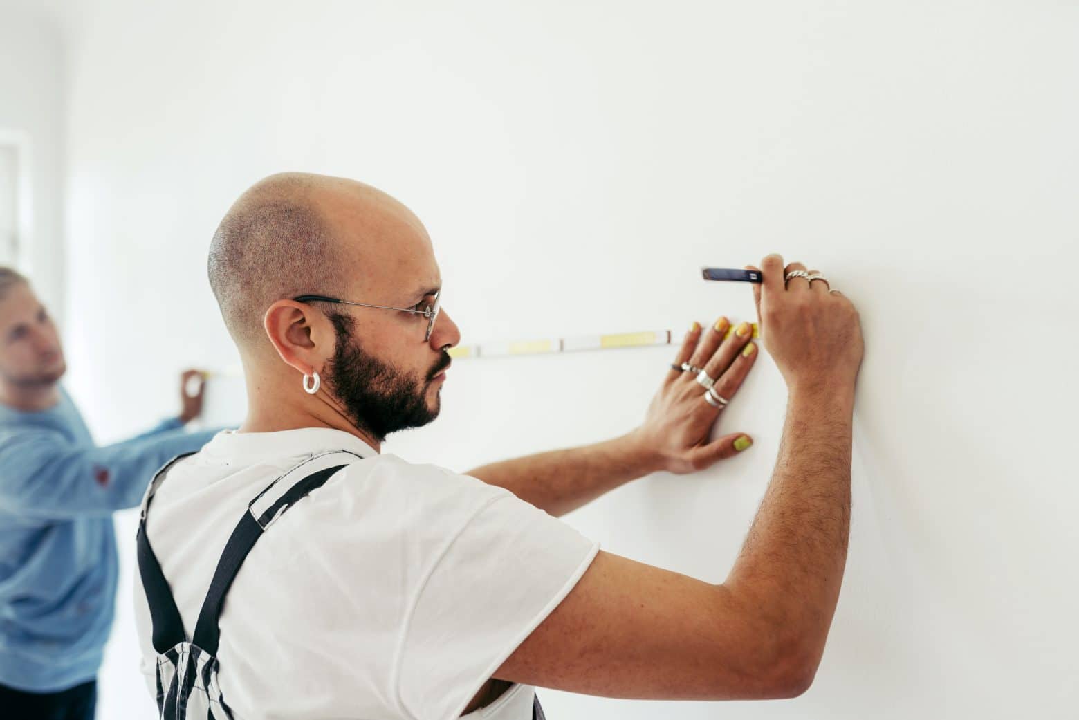 Un homme qui trace un trait au mur avec un mètre