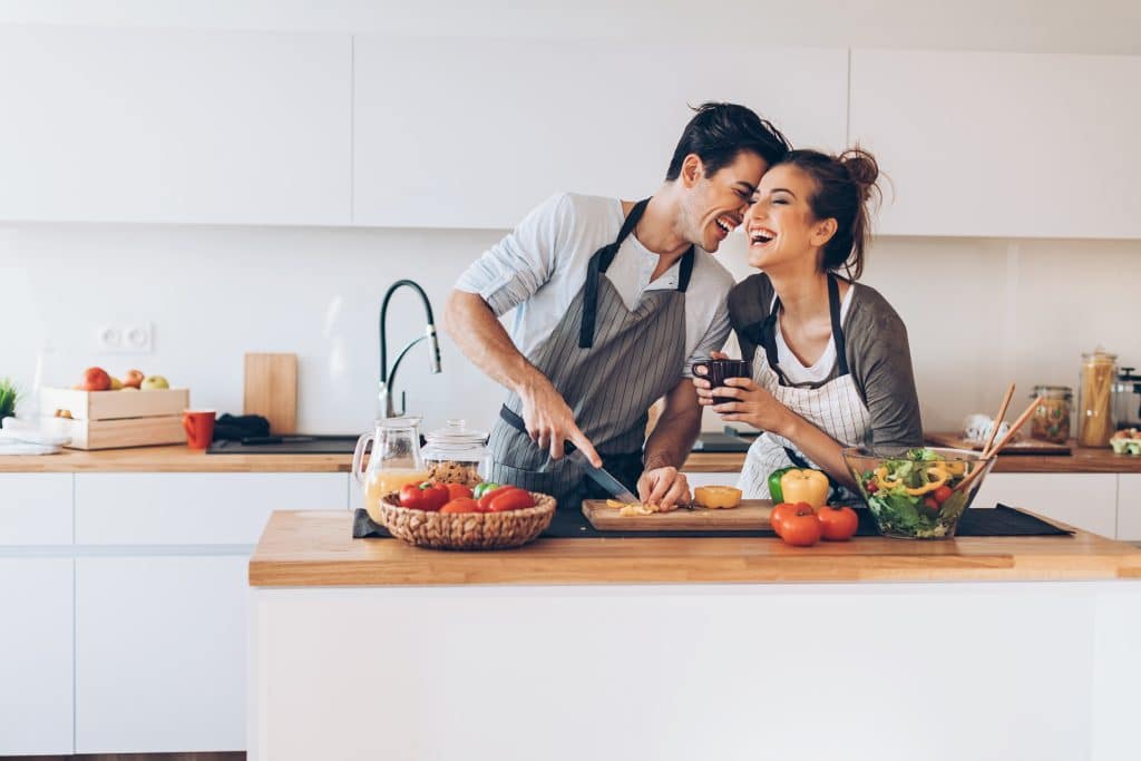 Un couple qui cuisine ne rigolant