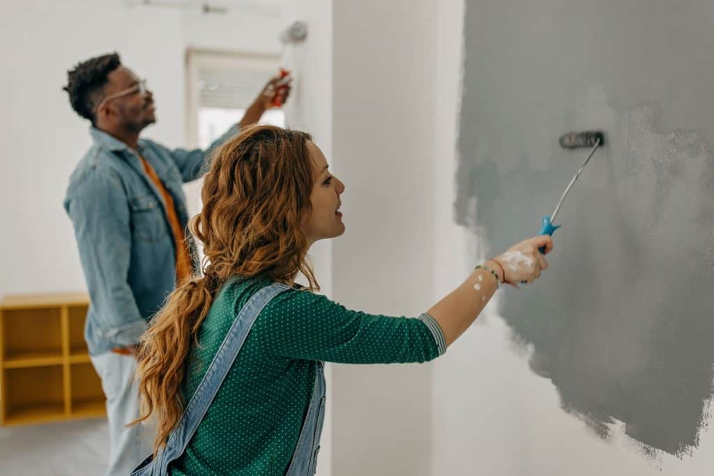 Une femme qui peint un mur en gris